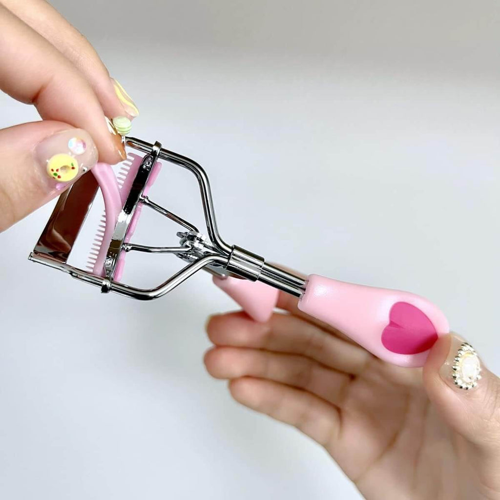 LashPro – Roestvrijstalen Wimperkruller in handen met roze handvatten en roestvrijstalen frame.
